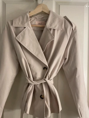 Beige trenchcoat från Nelly  - Aldrig kommit till användning, nyskick🩷 Köpt från Nelly för 799. Storlek S men passar även mig som är xs efter bandet i midjan är justerbart.               Postar efter 1-2 dagar med instabox, annars 3-4 dagar🩷