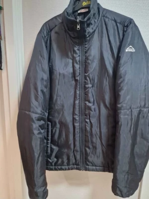 Svart pufferjacka från McKinley - Säljer en svart pufferjacka från McKinley med hög krage och dragkedja framtill. Jackan är tillverkad i syntetmaterial och har en clean look utan onödiga detaljer. Perfekt för kyliga dagar och enkel att matcha med olika outfits.