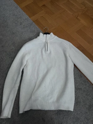 Vit ribbad polotröja 157 S - Vit ribbad polotröja från 157 i storlek S. Tröjan har lång ärm, hög krage och en half zip-dragkedja framtill. Perfekt för lager på lager och enkel att styla till olika outfits.