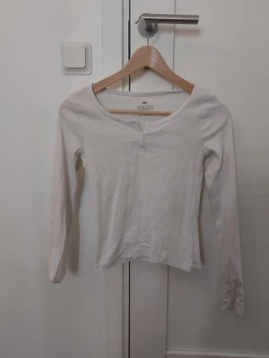 Vit långärmad topp från H&M - En enkel och stilren vit långärmad topp från H&M med rund halsringning och två knappar framtill. Aldrig använt❣️