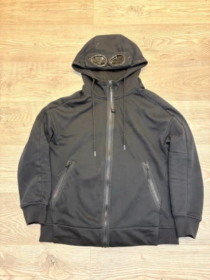 C.P. Company - Svart C.P. Company zip hoodie i storlek M. Super bekvämt material att ha på sig vardagligen och matchar till de flesta outfits!