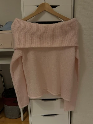 Ljusrosa offshoulder stickad tröja Gina Tricot - Supersöt ljusrosa stickad tröja från Gina Tricot i offshoulder-modell. Tröjan har bred ribbad kant upptill och långa ärmar. Perfekt för dig som vill ha en mysig men ändå stylish look.