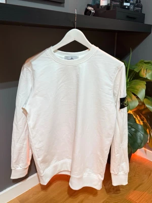 Vit sweatshirt från Stone Island - Säljer en clean vit sweatshirt från Stone Island med klassisk patch på vänster ärm. Storlek S. Använd fåtals gånger. Näst intil nyskick 