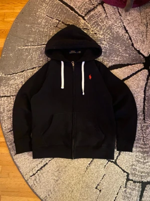 Svart Polo Ralph Lauren Hoodie - Säljer min svarta Ralph Lauren zip-up hoodie i Storlek L, men passar som en Medium. Drygt använd, inga skador. Vid frågor skicka ett DM! 