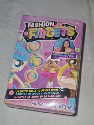 Fidget docka mystery  - Detta är en Fashion Fidgets docka, en leksak som kombinerar modedockor med fidget-funktioner. Det är en mystery vilken docka man får. Varje docka har minst 3-4 inbyggda fidget-egenskaper, som att poppa, vrida, dra eller snurra.  Det finns 18 olika dockor att samla i Serie 1.  Dockorna kommer med en praktisk klämma så att de kan fästas på till exempel en väska el dylikt. Helt ny!