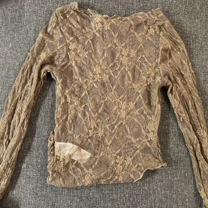 Beige spetsblus med lång ärm - Säljer en beige blus i spets med lång ärm och genombrutet mönster. Blusen har ett unikt blommigt spetsmönster och är figurnära i modellen. Perfekt för dig som gillar romantisk och bohemisk stil.