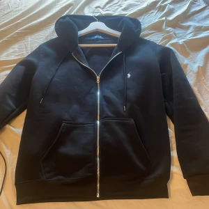 Svart hoodie från Polo Ralph Lauren - Svart hoodie från Polo Ralph Lauren. Riktigt stilren zip hoddie. Använd 1 gång. Priset kan diskuteras då det är riktigt snabb affär. Tveka inte på att skriva!