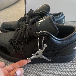 Nike Air Jordan 1 Low Svarta Sneakers - Snygga Nike Air Jordan 1 Low i helsvart med både matt och glansig finish. Skorna har klassisk snörning, ikonisk Jumpman-logga på tungan och detaljer i lackat skinn. Skorna är helt nya men fel storlek o råkat tas bort taggen som ni ser i kartongen så gick ej att returnera☺️Mycket fina skor skulle jag 100% säga o rekommenderar för er som har ögonen på dom, ser exakt ut som på bilden