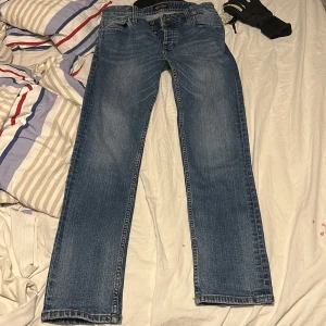 Blå slim fit jeans från Jack & Jones - Säljer ett par blå slim fit jeans från Jack & Jones, modell Tim. Jeansen har klassisk femficksdesign, snygga slitningar och raka ben. Tillverkade i jeansmaterial med en bekväm passform som passar perfekt till din vardagsstil.