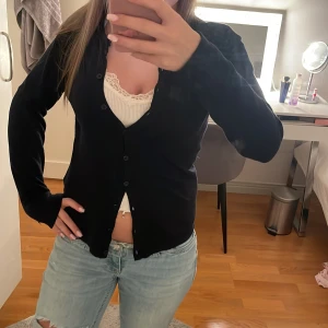 Marinblå kofta från Saint Tropez XS - En marinblå, klassisk kofta från Saint Tropez i storlek XS. Koftan har lång ärm och knäppning framtill med svarta knappar. Enkel och stilren modell som passar perfekt till jeans eller kjol. Mjuk och skön, troligtvis i bomull eller syntet.