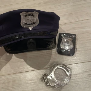 Poliskeps med badge och handbojor - Säljer en mörkblå poliskeps med silverfärgad badge där det står 'Special Police'. Kepsen har en blank svart skärm och ett dekorativt band framtill. Perfekt för temakvällar eller maskerad! Badge och handbojor i metall-look ingår. Perfekt till halloween 