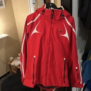 Röd vindjacka Goldwin XL - Röd skidjackafrån Goldwin i storlek XL med vita detaljer och dragkedjor. Jackan är som i nyskick. liten i storlek så passar mer M/L