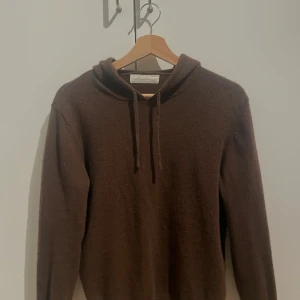 Brun kashmirhoodie från Sayless - Mysig brun hoodie från Sayless i lyxig kashmir. Tröjan har huva med snörning och långa ärmar, perfekt för kalla dagar. Enkel och stilren design som passar till allt. Supermjuk känsla och relaxed fit.