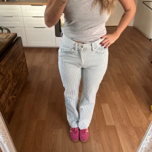 Randiga jeansbyxor i blått och vitt - Säljer ett par snygga ljusblå och vita randiga jeansbyxor med klassisk femficksdesign och låg midja. Byxorna är i straight fit!!💓 Knappt använda så dom är i nyskick. Finns en liten bleknings fläck som fanns när jag fick hem dom, men inget man tänker på (3e bilden)