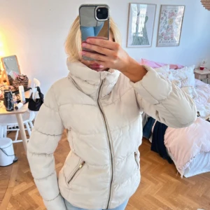 Beige pufferjacka med dragkedja - Snygg beige pufferjacka med hög krage och guldiga dragkedjor på fickorna. Perfekt jacka för höst och vinter💕💕