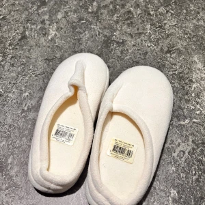 Vita mjuka ballerina-tofflor 38/39 - Supermysiga vita ballerina-tofflor i mjukt syntetmaterial. De har en enkel och rundad form med grå platt sula som ger skön komfort inomhus. Perfekta att glida runt i hemma när du vill ha det extra bekvämt.
