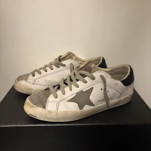 Golden Goose vita sneakers med stjärna - Golden Goose sneakers i vitt med grå mockadetaljer och en stjärna. JÄTTE BRA SKICK INGE HÅL INGA DEFEKTER, bara lite skitiga om sulan men går absolut att tvätta!