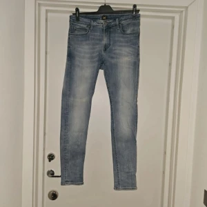 Lee Malone ljusblå slimfit  jeans W31 L32 - Säljer ett par Lee Malone slim jeans i ljusblå tvätt med snygga slitningar. Jeansen har klassisk femficksdesign, smal passform och är tillverkade i en stretchig mix av bomull, polyester och elastan för extra komfort. Priset går alltid att diskutera det är ba o skriva. 