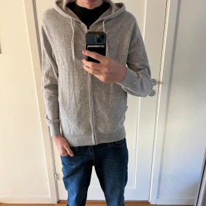 Grå Kashmir hoodie - Säljer denna zip-hoodie i Kashmir. Den är trendig och stilren. Använd sparsamt ett fåtal gånger och har inga defekter. Perfekt nu till höst och vinter.