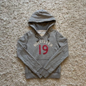 Grå hoodie från hollister - Snygg grå hoodie från hollister i mycket bra skick. Tror att det är en dam modell så därför sitter den lite mindre i storleken. Tveka inte på på o skriva vid frågor!