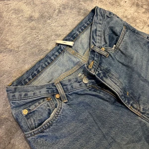 ljusblå jeans straight fit - Raka ljusblåa jeans med en cool V-formning framtill vilket skapar en smickrande siluett. Jeansen är från Weekday och har knappgylf, tydliga sömmar och den ikoniska läderpatchen bak i midjan. Perfekta för dig som gillar en tidlös och avslappnad look.