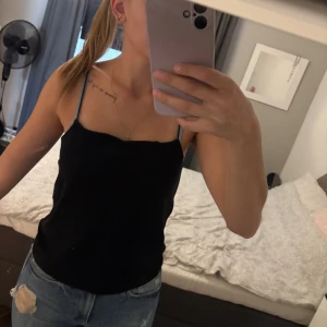 Linnen - Två stilrena linnetoppar i svart och ljusblått med smala axelband. Båda har en enkel, rak passform och är tillverkade i mjukt bomullsmaterial. Perfekt för dig som gillar minimalistisk stil och vill ha något lätt och bekvämt till sommaren.