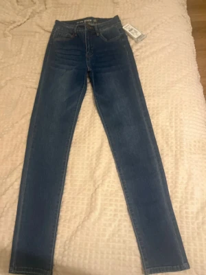 Mörkblå  jeans från Kappahl  - Snygga mörkblå skinny jeans från Kappahl med klassisk femficksdesign och hög midja. Jeansen har stretchigt material och smal passform hela vägen ner. 