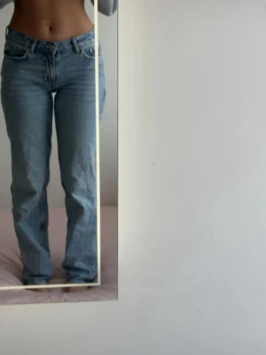 Ljusblå raka jeans med hög midja - Säljer ett par ljusblå jeans med raka ben och hög midja. Klassisk femficksmodell med knapp- och dragkedjegylf. Jeansen har en avslappnad passform och är perfekta för en trendig vardagslook.