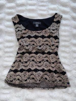 Vintage festtopp topp med guldpaljetter  - Supersnygg svart topp köpt på beyond retro med glittriga guldpaljetter och blommigt spetsmönster. Jättefin festtopp i superbra skick och passar storlek S-M!