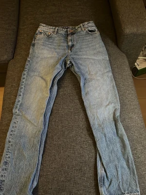 Jack & Jones ljusblåa jeans  - Klassiska Jack & Jones jeans i ljusblå denim med raka ben och femficksmodell. Jeansen har knappgylf och läderpatch bak i midjan. Perfekta för en avslappnad och tidlös stil.