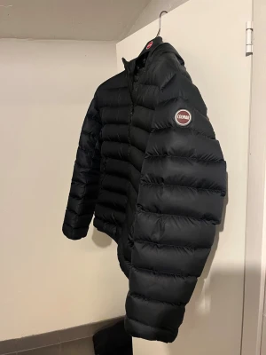 Svart dunjacka från Colmar - Snygg svart dunjacka från Colmar med quiltad design och dragkedja framtill. Jackan har två sidofickor med dragkedja och en liten logotyp på ärmen. Perfekt för kalla vinterdagar och riktigt lätt att bära. Nypris:4500kr