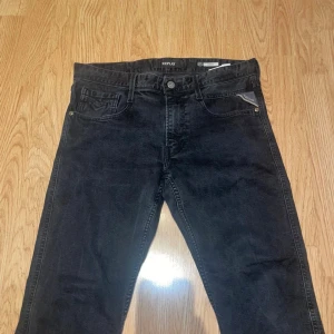 Svarta Replay straight fit jeans - Säljer ett par svarta jeans från Replay med klassisk femficksmodell och raka ben. Jeansen har Replay-logga på bakfickan och patch bak i midjan. Materialet är denim i bomull med en lätt tvättad look. Perfekta för en avslappnad och stilren outfit.