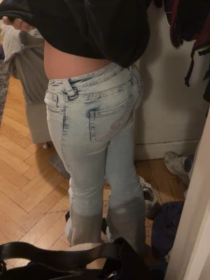 Ljusblå ultra low waist bootcut jeans - Säljer ett par ljusblå ultra low bootcut jeans med broderad bakficka. Jeansen. Materialet är denim och de har en snygg tvättad look som ger en cool vibe.
