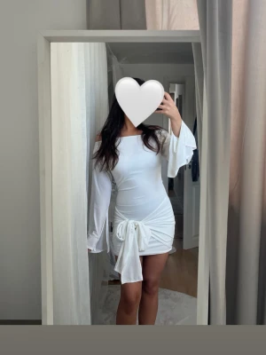 Vit kort klänning med knyt - Trendig vit kort klänning med långa utsvängda ärmar och snygg knytning i sidan. Offshoulder-modell som ger en modern look. Perfekt för dig som vill sticka ut med en stilren och chic outfit. Köpt här på plick, aldrig använd endast testad, med prislapp🤍