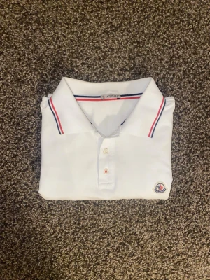 Vit Moncler pikétröja - Vit pikétröja från Moncler. Storlek S. Använd ett flertal gånger. Etiketten är något tvättad, inga defekter på resten av plagget. 8/10 skick.
