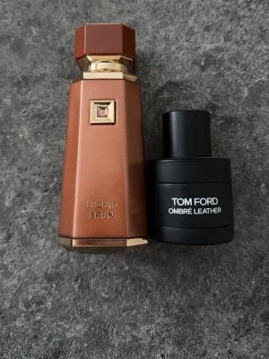 Tom Ford Ombré Leather 50ml parfym + Liquid Brun på köpet - Tom Ford Ombré Leather är en lyxig parfym i svart rund flaska med stilren design. Doften är djup och läderinspirerad, perfekt för dig som gillar unika och eleganta parfymer. Flaskan rymmer 50 ml Eau de Parfum. Slänger även in Liquid brun på köpet då jag aldrig använder nån av dessa. Köpte Tom Forden i italien 2023 så är en äldre batch och har fått macerateatat ett långt tag nu. Håller riktigt bra och är elegant. Skulle säga runt 40-35 ml kvar minst. Är öppen för byten och prisdiskussion