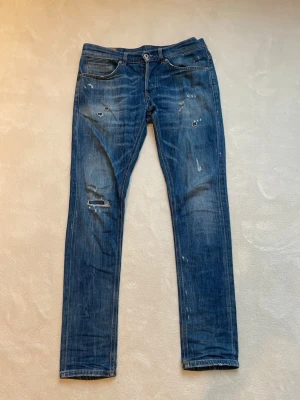 Dondup jeans - Säljer ett par riktigt nice blå dondup jeans med slitningar och distressed detaljer på både fram- och baksida. Jeansen har klassisk femficksdesign. 