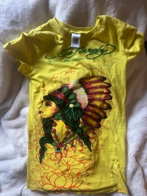 Gul Ed Hardy t-shirt med tryck - As cool gul t-shirt från Ed Hardy, i storlek S (barn) så skulle säga att den sitter som en XS/ tajt xs hållet , Klassisk passform och korta ärmar. En av mina favvo plagg, använd några gånger.