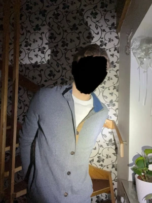 Grå kofta från Massimo Dutti - Snygg grå kofta från Massimo Dutti med knappar framtill och kontrastdetaljer i beige och blått vid knappslå och krage. Klassisk passform och ribbad mudd vid halsen. Perfekt för lager-på-lager och stilrena outfits.