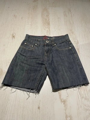 Mörkblå jeansshorts från Private - Säljer ett par mörkblå jeansshorts från Private med råa, fransiga benslut. Shortsen har kontrastsömmar och broderade detaljer på bakfickorna. Se mått på bild 3&4. Skriv för fler frågor 