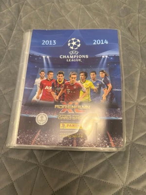 UEFA Champions League Adrenalyn XL 2013/2014 samlarpärm - Säljer en Panini Adrenalyn XL samlarpärm för UEFA Champions League 2013/2014. Pärmen innehåller massor av fotbollskort med spelare från olika lag och har en snygg framsida med Champions League-tema. Perfekt för dig som älskar fotboll och samlarkort!                                        Extremt bra skick, enbart suttit kvar i pärmen! Finns två limited edition kort som kan säljas separat eller i hela setet. Pris kan diskuteras vid snabb affär. 1500 utan limited edition 1900kr med. 