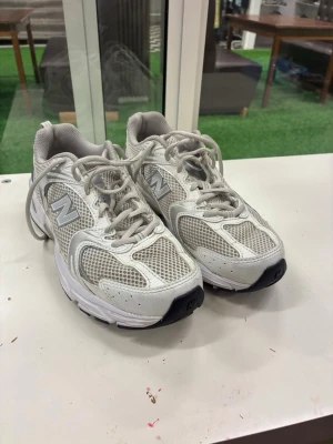 New Balance 530 vita sneakers - Säljer ett par New Balance 530 sneakers i vitt och silver med meshpaneler och syntetdetaljer. Klassisk chunky sula och reflekterande detaljer. Skorna har snörning och rund tå, perfekta för en sportig och trendig look.