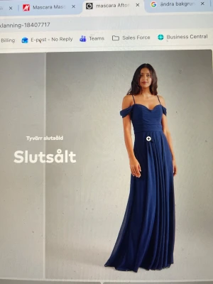 Mascara festklänning navy - Elegant mörkblå aftonklänning från Mascara med smala axelban, offshoulder-detaljer och slits fram. Klänningen har ett draperat liv och v-ringning både fram och bak. Perfekt för bal, sittning eller festligare tillfällen. Använd en gång. 