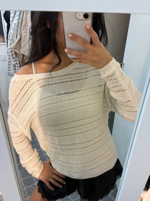 Beige stickad tröja med hålmönster - Säljer en beige stickad tröja med snyggt hålmönster och avslappnad passform. Tröjan har lång ärm och bred halsringning som kan bäras offshoulder. Perfekt att slänga över ett linne eller en bikini. 