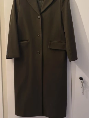 Kappa - Lång, klassisk svart kappa från Cream med rak passform och tre knappar framtill. Kappan har bred krage, två fickor med lock och dekorativa knappar vid ärmslut. Perfekt för dig som gillar stilrena och tidlösa plagg.