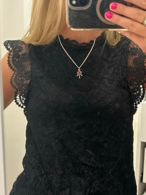 Fest topp - Säljer en svart super snygg fest topp i spets med fina volangärmar och detaljerad brodyr. Toppen är ärmlös med rund halsringning. Perfekt för fest eller middag!