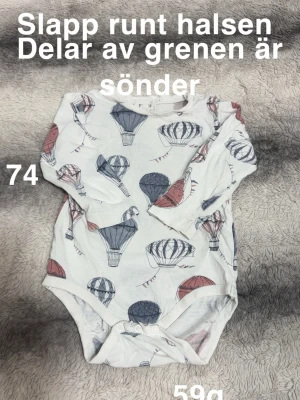 Vit långärmad body med luftballonger - Supersöt vit långärmad body från Newbie med tryck av blå och röda luftballonger. Bodyn har rund hals och tryckknappar i grenen för enkel påklädning. perfekt för små äventyrare.🌸 Slappare runt halsen. Grenen är sönder. Storlek 74