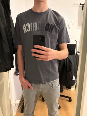 Mörkgrå Hoodrich t-shirt - Säljer en mörkgrå t-shirt från Hoodrich med tryck på bröstet. Ganska stor i passformen men riktigt schysst. 