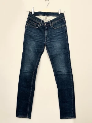 Acne Studios blå jeans slim fit - Snygga blå jeans från Acne Studios med klassisk femficksdesign och slim fit. Jeansen är gjorda i robust denim av bomull. Perfekta för dig som gillar en clean och tidlös look. Acne Studios-logga på bakfickan och insidan. Storlek 30(31)/32