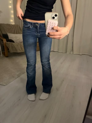 Blå bootcut jeans från ONLY - Snygga blå jeans från ONLY med bootcut-modell och låg midja. Jeansen har klassisk femficksdesign, dragkedja och knapp framtill. Materialet är jeans med lätt tvättade detaljer för en cool look. Har en två små hål vid bakfickornas kanter, syns knappt men är lätt o fixa!! Strl xs/30